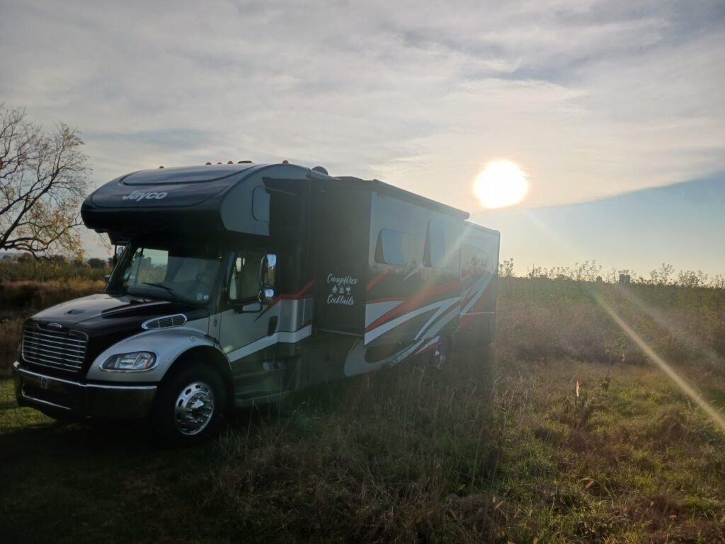 rv in a field with the sunset